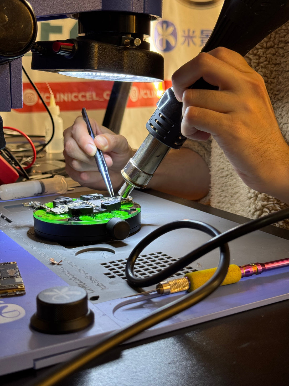 Técnico ClinicCel realizando microsoldadura en placa iPhone con estación de aire caliente en laboratorio Providencia Santiago