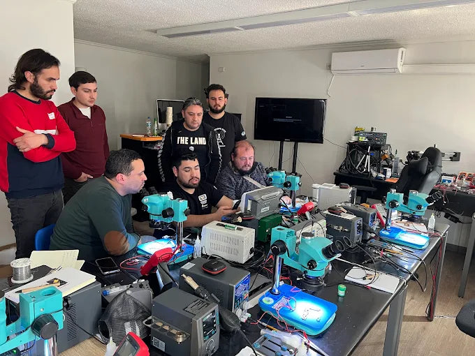 Clase practica del curso de microsoldadura: alumnos trabajando con microscopios trinoculares y estaciones de soldadura
